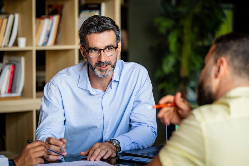 Mid adult businessman with beard and glasses, wearing blue shirt, listening and concentrating in meeting